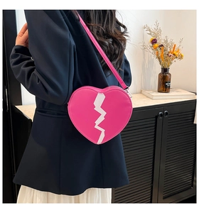 Détail du sac à bandoulière rose en forme de cœur avec motif cœur brisé blanc cousu