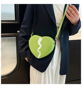 Detail view of a light green heart-shaped crossbody bag with white lightning patterns