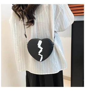 Détail du sac à bandoulière noir en forme de cœur avec un motif d'éclair blanc sur cuir