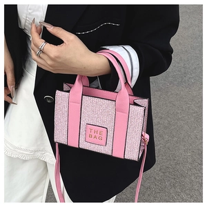 Detailed view of a pink tweed tote bag with leather straps worn by a model