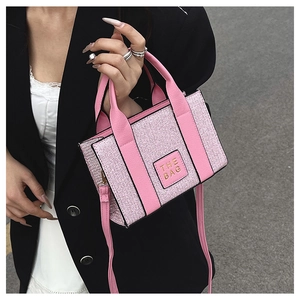 Detail of pink woven fabric texture and THE BAG leather label on square tote bag