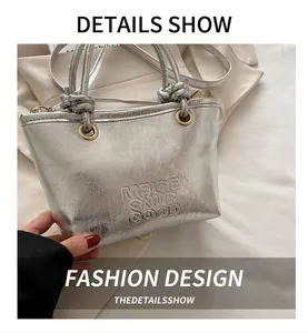 Detailed view of silver pleated bucket bag featuring embossed logo and metallic ring hardware