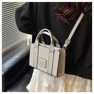 Silver glitter crossbody tote bag with 'THE BAG' patch shown on model