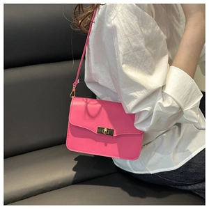 Hot pink matte leather crossbody bag with gold twist lock shown on a model's shoulder