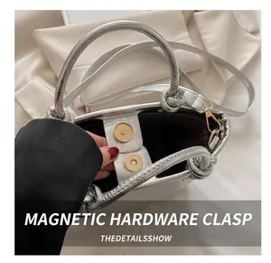 Close-up of the secure golden magnetic snap closure on a textured silver bucket bag