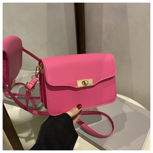Detailed view of magenta rectangular bag featuring gold metallic twist lock and smooth leather
