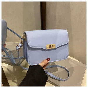 Close-up of light blue crossbody bag with gold-tone metal lock and fine leather strap
