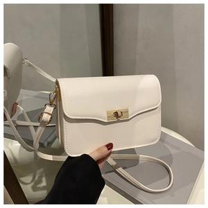 Detail of white leather crossbody bag showing golden twist lock and smooth texture