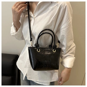 Dettaglio borsa a secchiello nera con logo MEIGE SNUR GOOD e finiture dorate