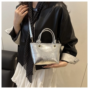 Close-up of silver mini bucket bag featuring embossed text and pleated metallic texture