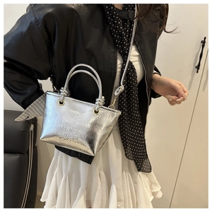 Silver textured leather tote bag with embossed lettering shown on model for street style