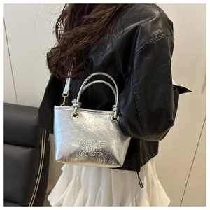 Detail of silver textured bucket bag featuring embossed lettering and golden hardware accents