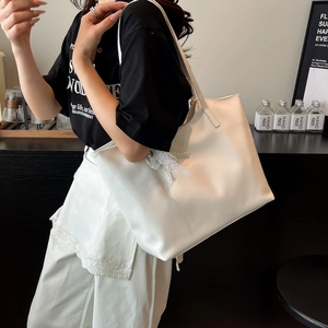 Minimalist cream white large tote bag with lace bow accessory worn by a model