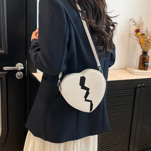 Fashionable heart-shaped white crossbody bag with black lightning detail worn by a model