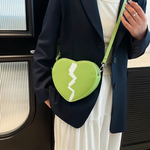 Green heart-shaped crossbody bag with white lightning pattern on navy blazer outfit