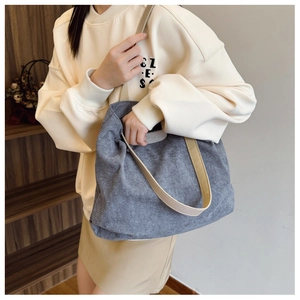 Detail of grey corduroy tote bag featuring 'FASHION' tag and beige canvas handles
