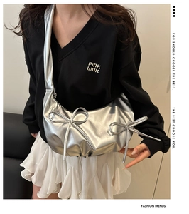 Detailed view of silver crescent bag with pleated bow and metallic leather texture