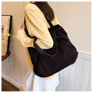 Close-up of black corduroy tote bag with wide shoulder strap showing fabric texture