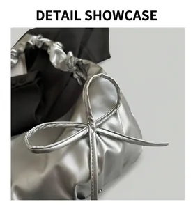 Close-up of metallic silver pleated cloud bag with scrunchie handle and bow detail