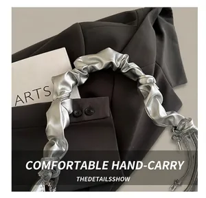 Detail shot of the shiny silver pleated strap on a metallic leather hobo shoulder bag