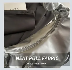 Macro view of metallic silver cloud bag showing glossy leather texture and knotted handle