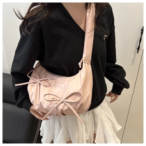 Detail of pink bow-knot crossbody bag with light-reflective fabric and wide strap