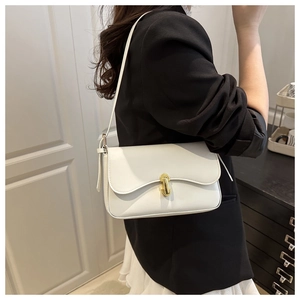 Detail of white leather shoulder bag featuring elegant gold U-shaped metal buckle closure