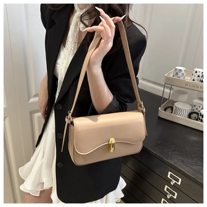 Close-up of elegant apricot shoulder bag with a polished golden oval swivel lock
