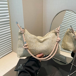 Woven straw shoulder bag with pink leather strap shown in a minimalist studio setting