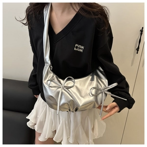 Silver metallic crescent shoulder bag featuring stylish bow details and a sleek modern design