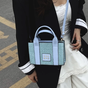 Minimalist light blue small tote bag with gold lettering shown in street style outdoor scene
