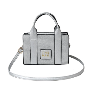 Silver metallic rectangular tote bag with THE BAG logo and adjustable shoulder strap