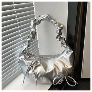 Close-up of silver crescent bag featuring drawstring bows and metallic pleated straps