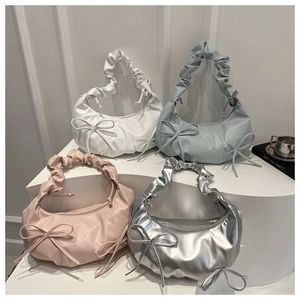 Detailed view of half-moon pleated bags with bow tie accents in four stylish colors