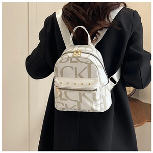 Detail of white mini backpack with gold rivets and letter prints on a black blazer
