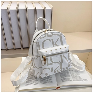 Close-up of white leather backpack with letter print and golden rivet zipper pocket