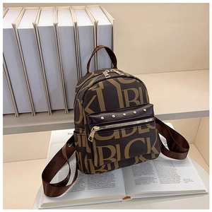 Mini vintage backpack with letter prints and gold studs on an open magazine background