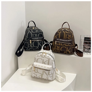 Three mini backpacks in black, brown, and white with letter prints and gold rivets