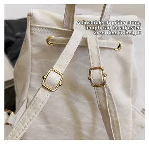 Detail view of adjustable shoulder strap and gold hardware on white nylon backpack