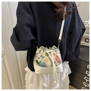 Detail of floral tapestry bucket bag with drawstring closure and golden metal hooks