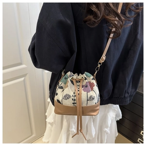 Detail of floral jacquard bucket bag with drawstring closure and brown leather straps