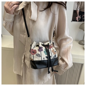 Detail of a chic bucket bag with floral jacquard fabric and black leather trim