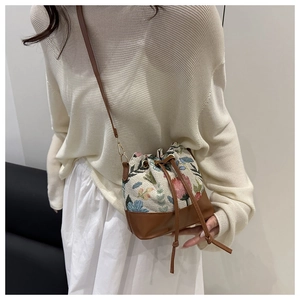 Detail of floral linen bucket bag with brown leather drawstring and shoulder strap