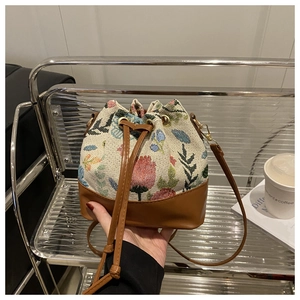 Detailed close-up of floral jacquard embroidery and brown faux leather bucket bag