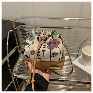 Close-up of ethnic floral drawstring bucket bag with leather trim and shoulder strap