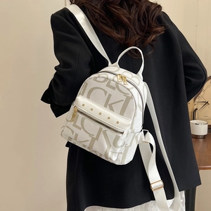 White mini backpack with letter prints and gold studs shown on a model outdoors