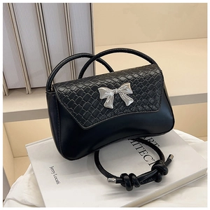 Detail of black woven leather handbag featuring a silver bow buckle and dual handles