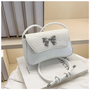Close-up of white crossbody bag featuring woven texture and silver metal bow detail