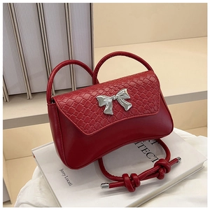 Detail of red shoulder bag with woven flap texture and silver metallic bow ornament