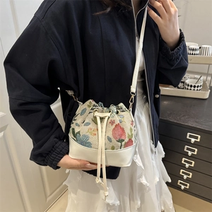 Minimalist bucket bag with vintage floral embroidery and white leather paneling